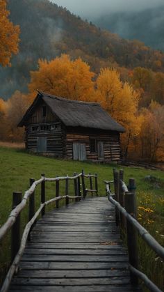 a wooden walkway leading to a log cabin in the woods with fall foliage around it