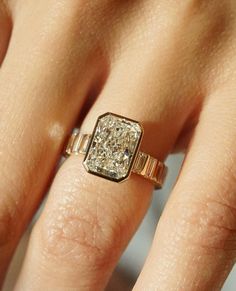 a woman's hand with a diamond ring on top of her finger and an engagement band