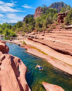 people are swimming in the river near some rocks