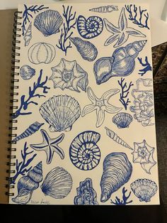 a notebook with blue ink drawings of shells and corals