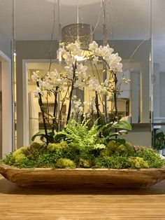 a wooden bowl filled with white flowers and greenery