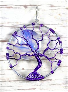 a glass and wire tree of life pendant on a white wooden background with purple beads