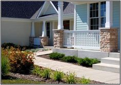 a house with stone steps leading up to the front door and landscaping area in front