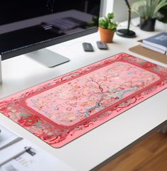 a desk with a computer monitor, keyboard and mouse on it in front of a pink rug