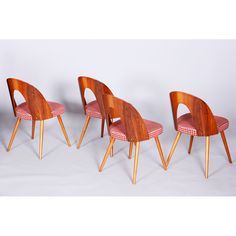 four wooden chairs with red and white checkered seat covers, one is bent to the side