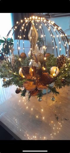 a christmas arrangement with pine cones and lights in a birdcage on a table