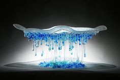 an artistic glass sculpture with blue and white drips on it's surface, in the dark