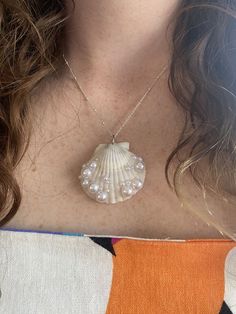 a close up of a person wearing a necklace with a shell on the back of her neck