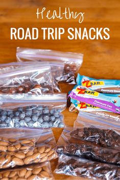 healthy road trip snacks in plastic bags on a wooden table with text overlay that says healthy road trip snacks