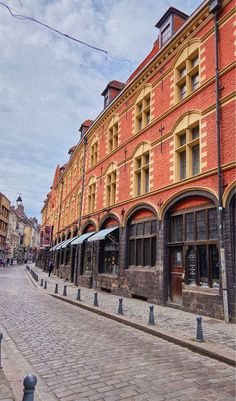 an old brick building on the corner of a city street with cobblestone streets