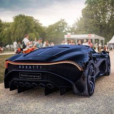 a very cool looking car parked on the side of a road with people in the background