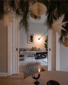 a living room filled with furniture and a christmas tree hanging from the ceiling next to a doorway