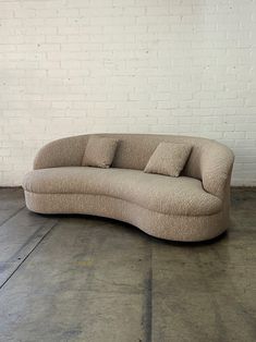 a curved couch sitting in front of a white brick wall