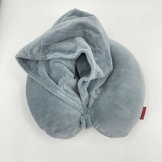 a gray pillow with a hood on it sitting on a white surface next to a red object