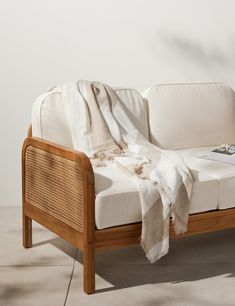 a white couch sitting on top of a floor next to a wooden frame and pillow