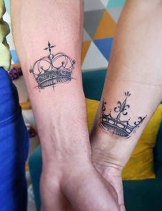 two people holding hands with tattoos on their arms and one has a crown tattooed on the wrist