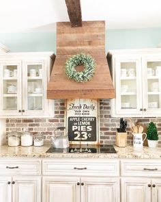 a kitchen with white cabinets and a wooden oven hood in the middle of the counter