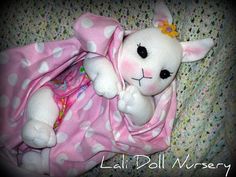 a white stuffed animal laying on top of a pink and white blanket covered in polka dots