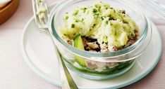 a glass bowl filled with food sitting on top of a white plate next to silverware