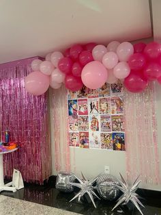 balloons and streamers are hanging from the ceiling in front of a pink curtain with pictures on it