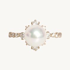 a pearl and diamond ring on a white background