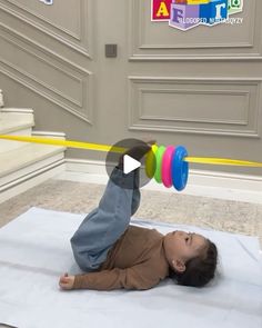 a baby is laying on the floor playing with some toy dumbbells in front of him