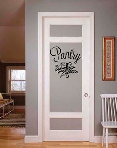 a door with the word pantry painted on it in black and white, next to a chair