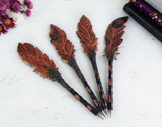 four wooden arrows with designs on them are sitting next to flowers and a black case