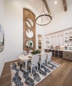 a dining room table with white chairs in front of a large mirror on the wall