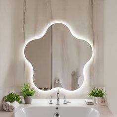 a bathroom with a sink, mirror and potted plants on the counter in front of it