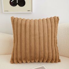 a white couch with a brown pillow on top of it and a clock above the pillows