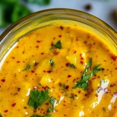 a glass jar filled with yellow sauce and garnished with parsley