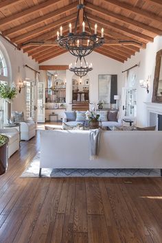 a living room filled with lots of furniture and a chandelier hanging from the ceiling