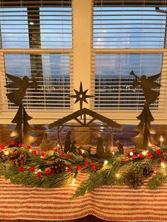 a table topped with christmas decorations next to a window covered in shutters and pine cones