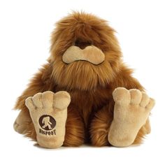 a brown stuffed animal sitting on top of a white floor next to a pair of feet