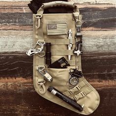 an army pouch filled with various items on top of a wooden table next to a knife