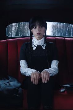 a woman sitting in the back seat of a car with her hands on her knees