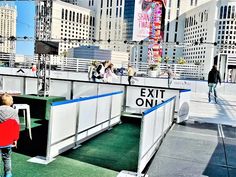 people are standing on the roof of an exit only sign in front of some tall buildings