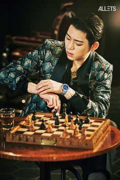 a man sitting at a table with a chess board in front of him and his hand on the queen's chest