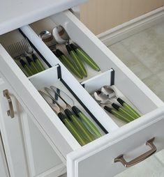 an open drawer with utensils and spoons in it on the counter top