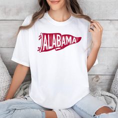 *Also available as a sweater. See below.* This Alabama Pennant T-Shirt is perfect for showing off your love for the Crimson Tide! Featuring a vibrant pennant flag design, this t-shirt is made of soft and comfortable fabric. Show your team pride in style with this unique and playful t-shirt. White Game Day Fan Apparel T-shirt, White Fan Apparel T-shirt For Game Day, White T-shirt For Team Spirit Fan Gear, White T-shirt For Fan Gear With Team Spirit, White T-shirt For Sports Fans, White Screen Print T-shirt For Game Day, School Spirit White T-shirt For Sports Events, Sports Fan White T-shirt For Fan Merchandise, Pre-shrunk White Sports Fan T-shirt