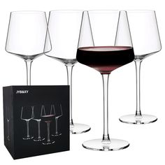 four wine glasses with different types of wine in them next to a black gift box