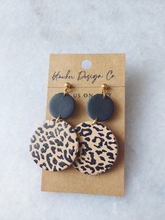 the leopard print and black circle earrings are shown on top of a cardboard card with a tag