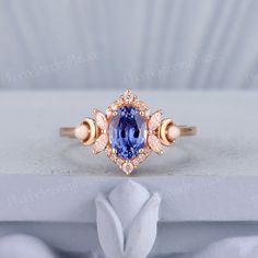 a tan gold ring with an oval blue sapphire surrounded by smaller round pink diamond accents