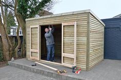 a man standing in the doorway of a shed with his hands up to the sky