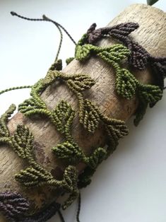 a piece of wood that has some green and purple beads attached to it with string