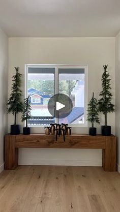 a living room filled with furniture and plants on top of a wooden table in front of a window