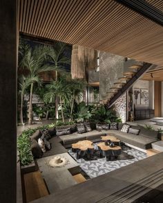 a living room filled with lots of furniture next to a stair case and palm trees