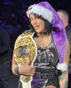 a woman wearing a santa hat and holding a wrestling belt