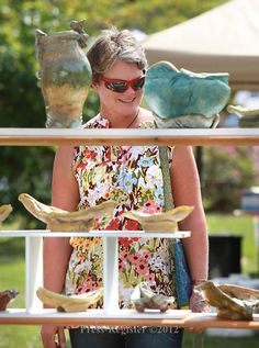 a woman standing in front of an assortment of vases